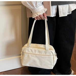 Detail view of cream canvas shoulder bag with silver zippers styled with a casual outfit