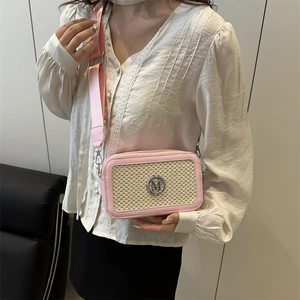 Sac bandoulière rose avec texture tissée beige et logo M argenté porté par un mannequin