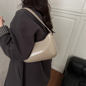 Chic beige leather shoulder bag with embossed fashion text shown in a lifestyle setting