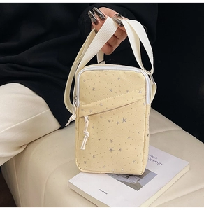 Detail of pale yellow canvas crossbody bag with star pattern and knotted zipper pull