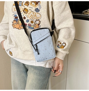 Detailed side view of a light blue crossbody bag with silver star prints on a model