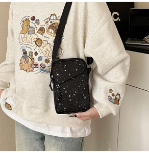 Close-up of a black canvas crossbody bag with star pattern and double zipper design