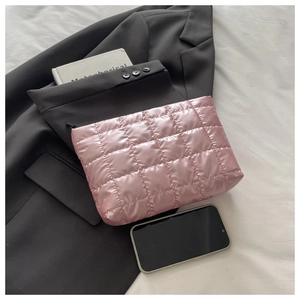 Pochette trapuntata rosa con finitura metallica mostrata con telefono e blazer