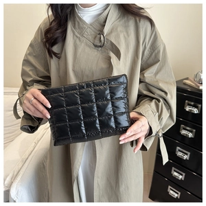 Close-up of a black quilted puffer clutch bag in a modern home interior setting