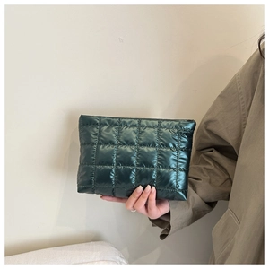 Dettaglio di una pochette trapuntata verde con finitura metallizzata e chiusura a zip