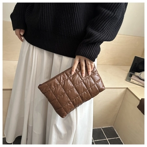 Close-up of a brown quilted handbag with luxury checkered pattern and zipper detail