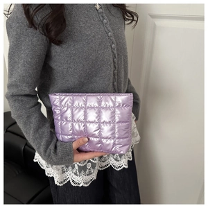 Close-up of lavender purple quilted metallic cosmetic bag held by a person in a casual setting