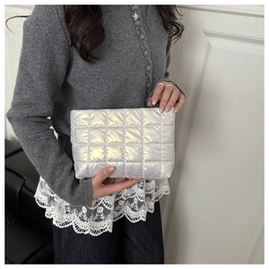 Close-up of a silver quilted makeup bag with metallic finish held by a model