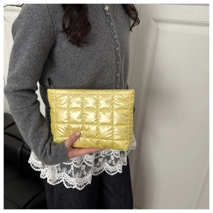 Detail of yellow quilted makeup bag with glossy texture and black zipper closure