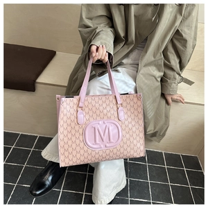 Detail view of pink tote bag featuring all-over M letter print and embossed logo