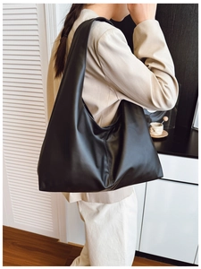 Side view of a black minimalist hobo shoulder bag made of soft matte PU leather on a model