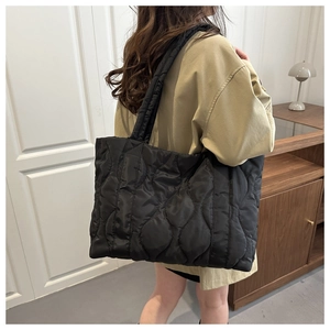 Detailed view of large black quilted tote bag with wavy stitching for chic casual style