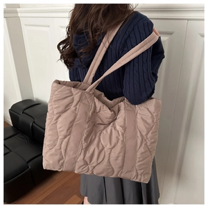 Detail of coffee latte down-quilted tote bag featuring soft wavy stitching and wide strap