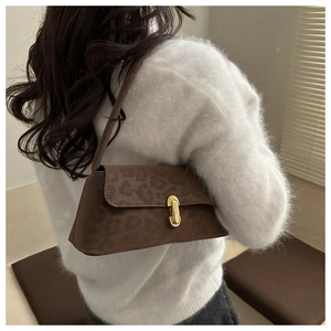 Détail du sac léopard marron sous le bras avec fermoir doré et texture élégante