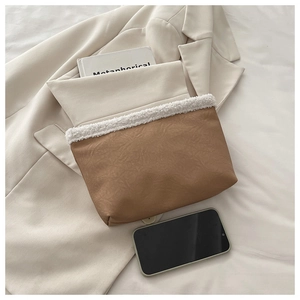 Close-up of brown envelope clutch with white faux shearling trim and textured PU leather
