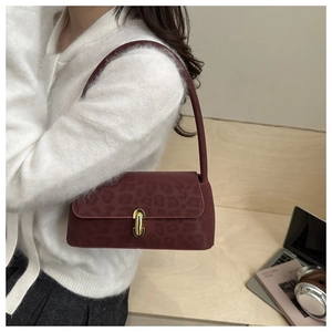 Detail of burgundy leopard print shoulder bag with vintage gold clasp on wood desk