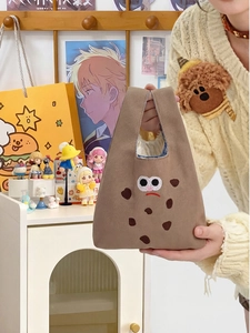 Close-up of a cute biscuit-shaped brown canvas handbag with embroidered eyes and mouth