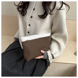Close-up of minimalist brown textured clutch with white plush faux fur trim detail