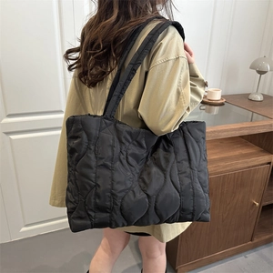 Large black quilted tote bag for women with wave pattern and wide shoulder strap