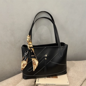 Black leather tote bag with white contrast stitching and decorative patterned silk scarf