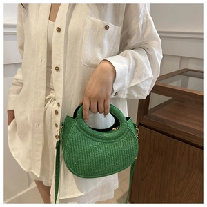 Détail d'un sac à main tressé vert vif avec paillettes et bandoulière sur tenue en lin blanc