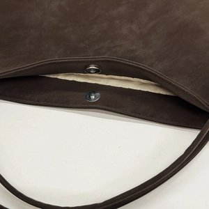 Detail view of the silver magnetic buckle closure on a premium brown leather handbag