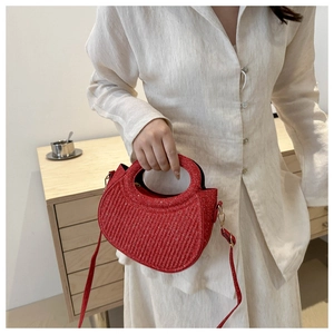 Détail du sac à main rouge en demi-lune avec texture plissée et finitions dorées