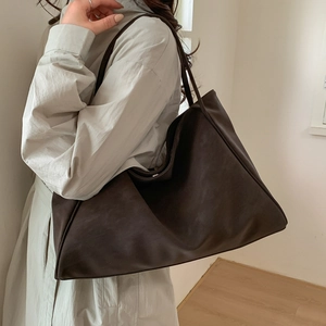 Retro brown large capacity tote bag in matte leather finish worn on shoulder by model