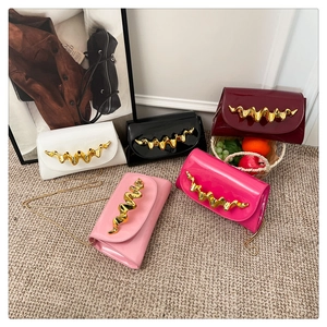 Detailaufnahme modischer Lackleder-Abendtaschen mit goldenen Wellen-Metallbeschlägen