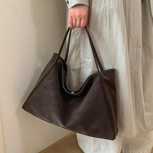 Close-up of dark brown oversized tote bag showing fine stitching and metal magnetic closure