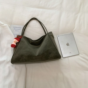 Detail of olive green suede tote bag with apple plush charm and tablet for size scale