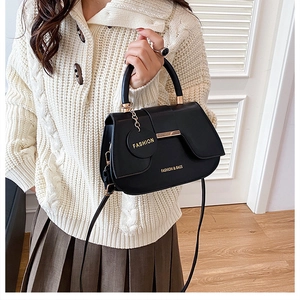 Close-up of black saddle bag with gold metal buckle and fashion charm detail
