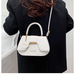 Vue arrière d'un sac bandoulière blanc sur un blazer noir avec boucle en métal doré