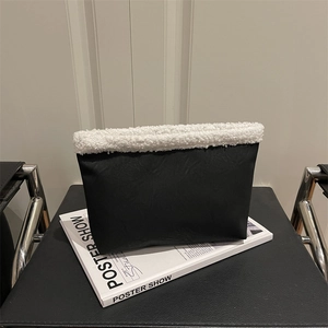 Pochette minimalista in pelle nera con bordo in peluche bianco su un supporto espositivo