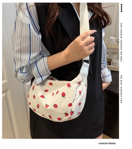 Detail of corduroy shoulder bag with red strawberry pattern and woven wide strap