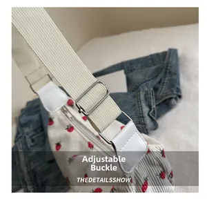 Close-up of the adjustable silver buckle and strawberry print on white corduroy bag