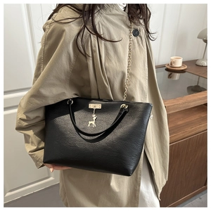Detailed view of black lychee leather tote bag with gold chain and deer charm