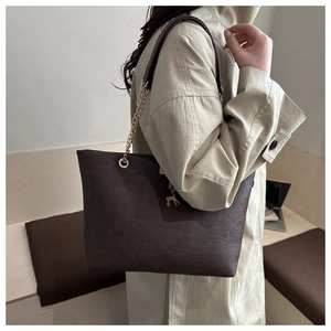 Detail of dark brown tote bag featuring lychee texture leather and a gold deer charm