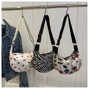 Detailed view of crescent shoulder bags in strawberry, zebra and floral patterns
