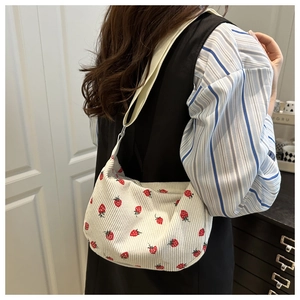 Detailed shot of cream corduroy crossbody bag featuring red strawberry embroidery accents