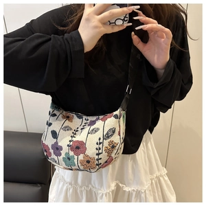 Detail of a retro floral woven crossbody bag with colorful patterns and black strap
