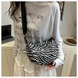 Detail of zebra pattern crossbody bag with wide black strap on model in cozy setting