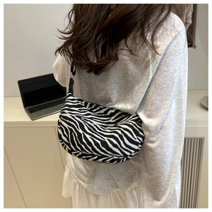 Detail of a zebra print shoulder bag with a stylish half-moon shape and knit texture