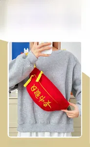 Détail du sac de poitrine en toile rouge avec broderie jaune et tirette de fermeture