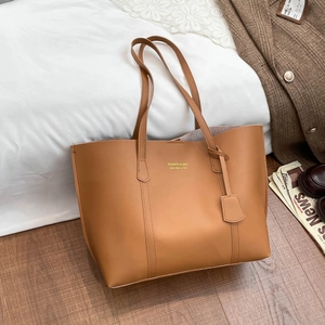 Brown minimalist leather tote bag with gold lettering in a cozy home setting