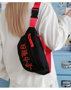 Détail du sac bandoulière avec broderie rouge et sangle en nylon assortie en mode lifestyle