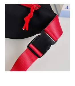 Gros plan sur la boucle noire et la sangle tissée rouge d'un sac banane bandoulière