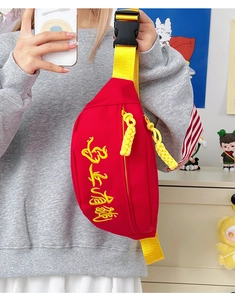 Détail du sac bandoulière rouge avec broderie jaune et bandoulière tissée
