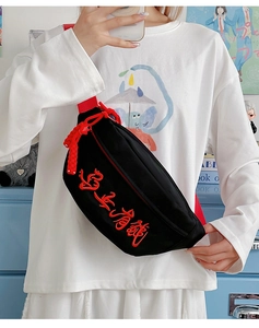 Détail du sac bandoulière en toile noire avec broderie rouge et gland à franges assorti