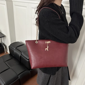 Wine red faux leather tote bag with gold deer pendant and chain strap on shoulder